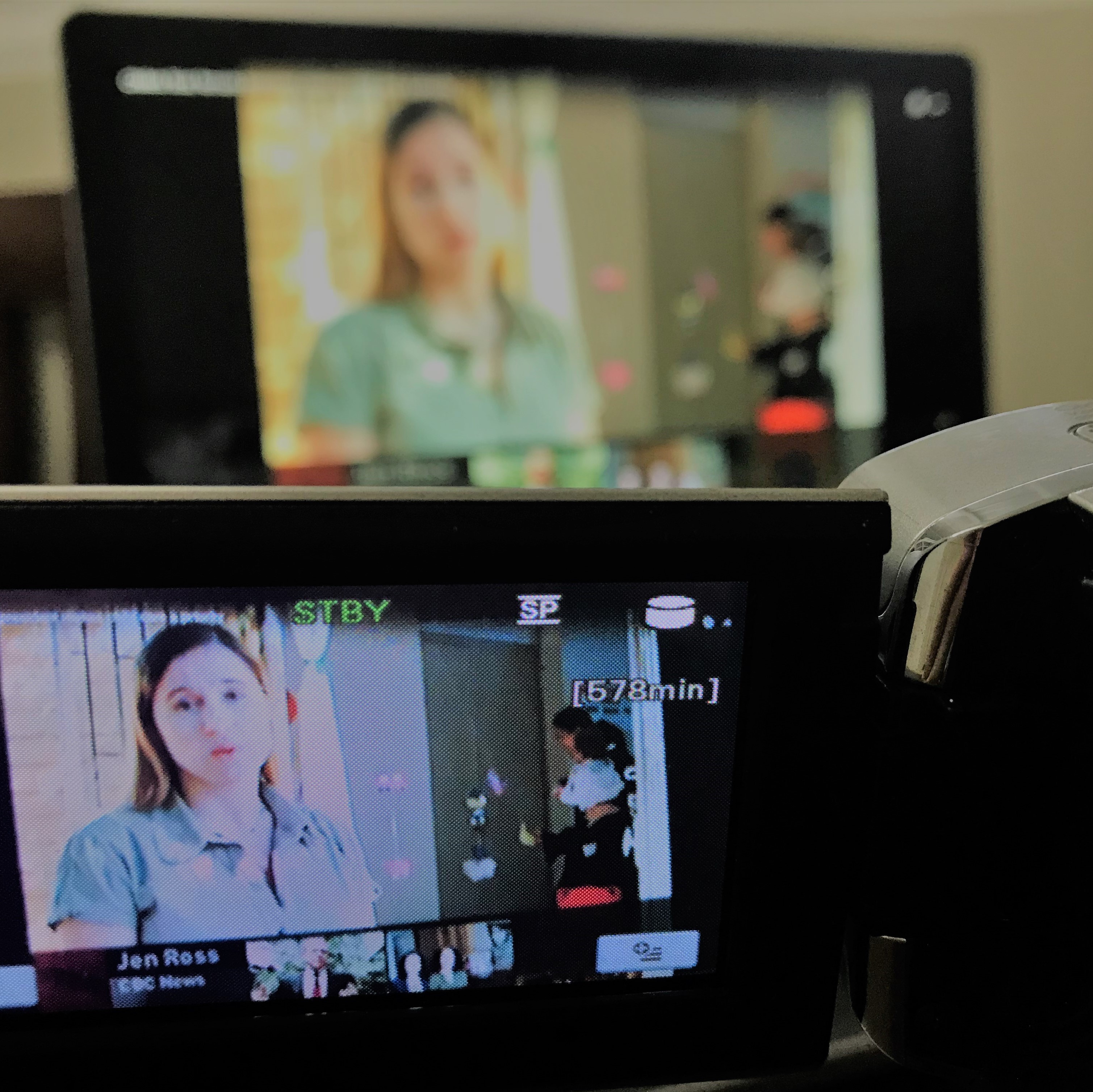 View from behind a video camera of a television screen where Jen Ross is doing a stand-up for one of her TV documentaries.